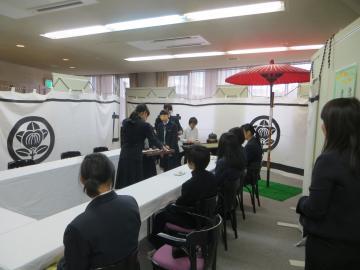 赤い和傘をたてて来場者にお茶をふるまっている女子高生の写真