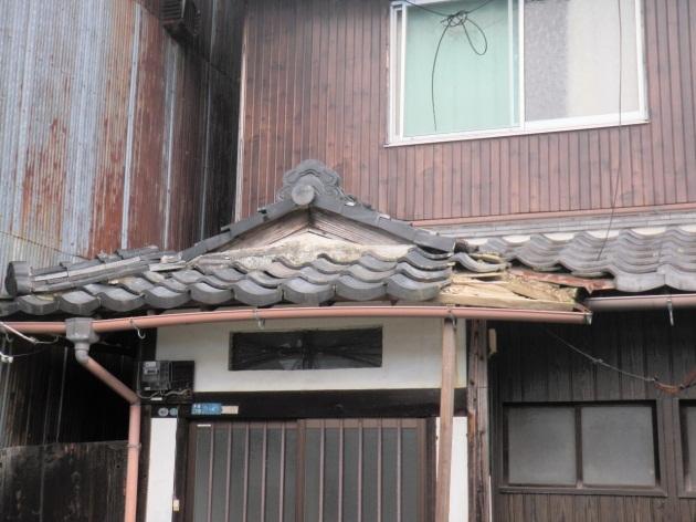 屋根の端の瓦が落ちてしまい、危険な状態の空き家の写真