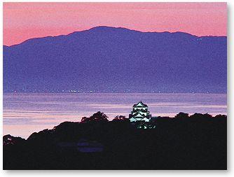 背景に白亜三層を望む夕日に彩られた美しい彦根城の写真