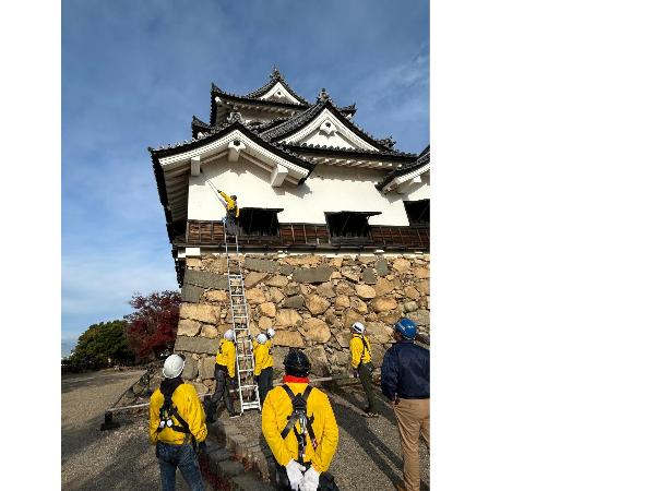 城の壁面にはしごをかけてすす払いをしている様子