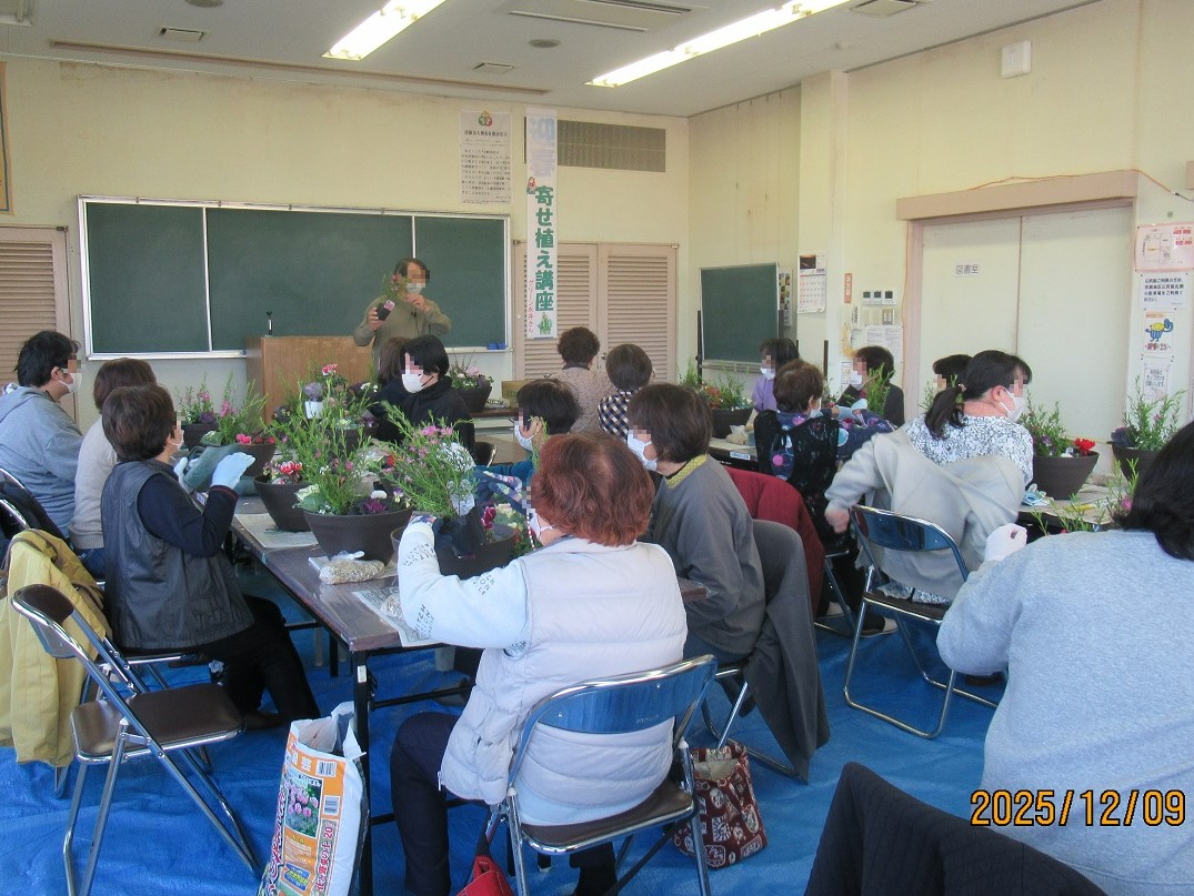 寄せ植えの説明をする講師と椅子に座って話を聞く参加者