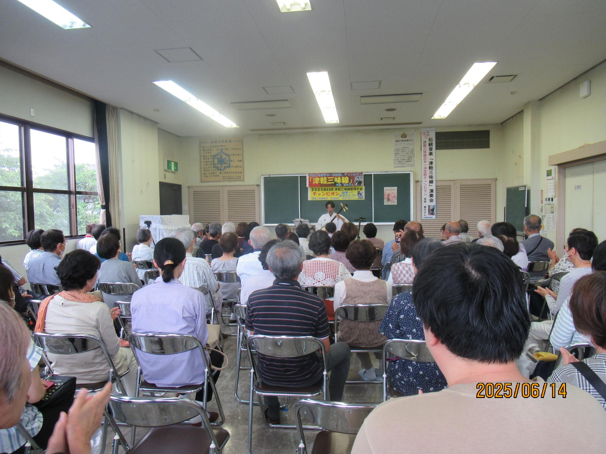 会場後部から椅子に座る聴衆を写した写真