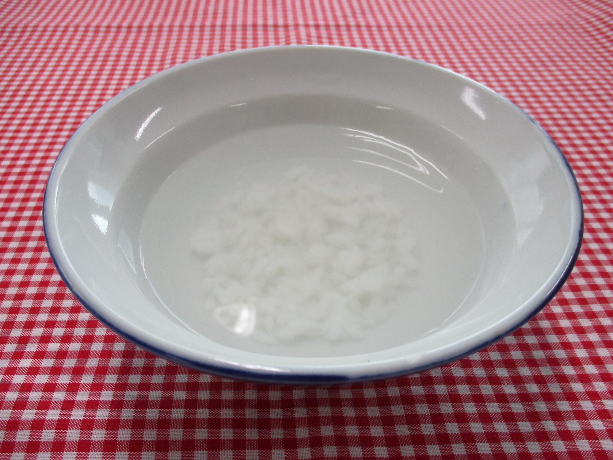 深めの皿に米と水が入っている画像