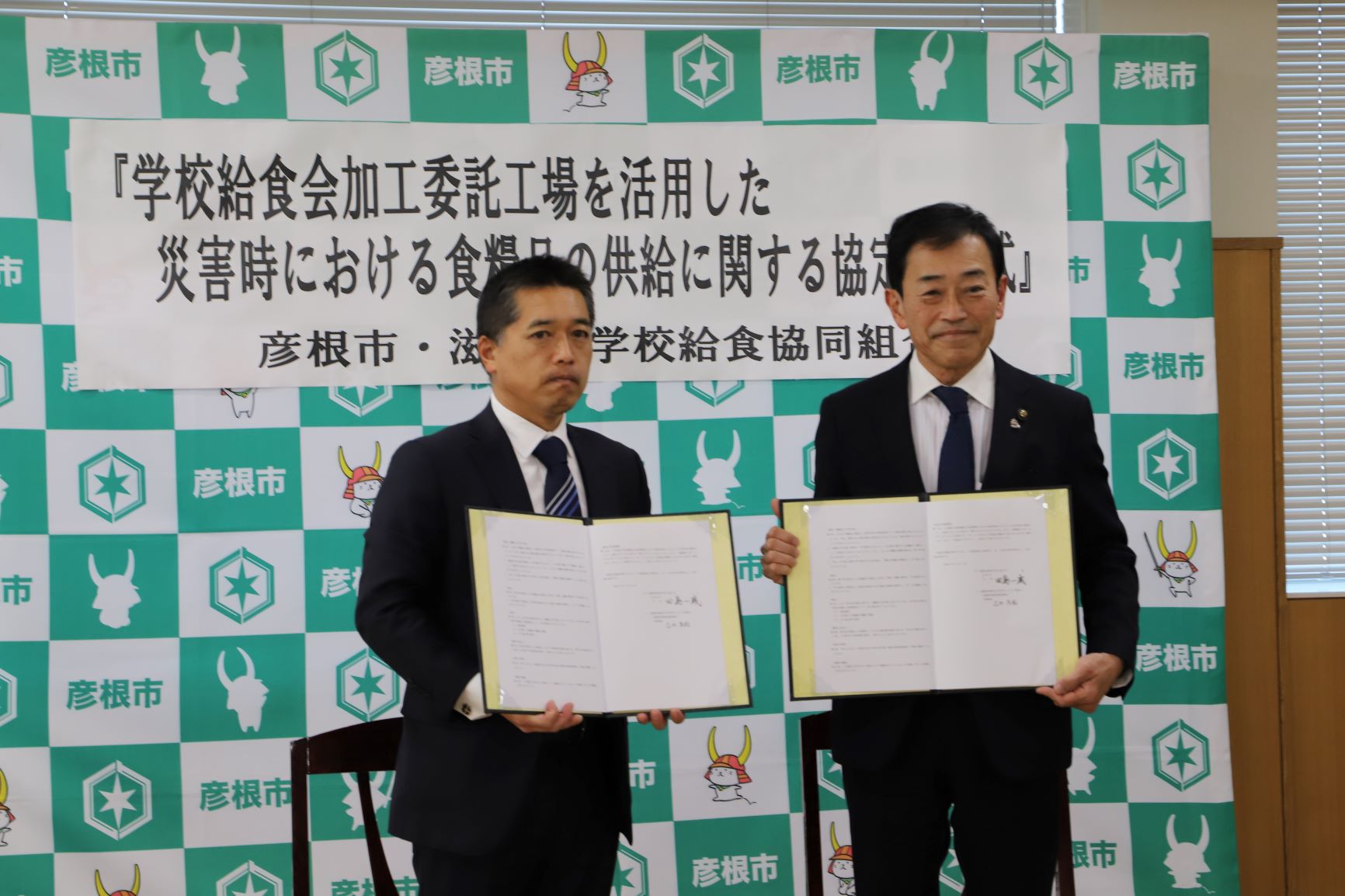 市長と協定先出席者が協定書を開いているところ