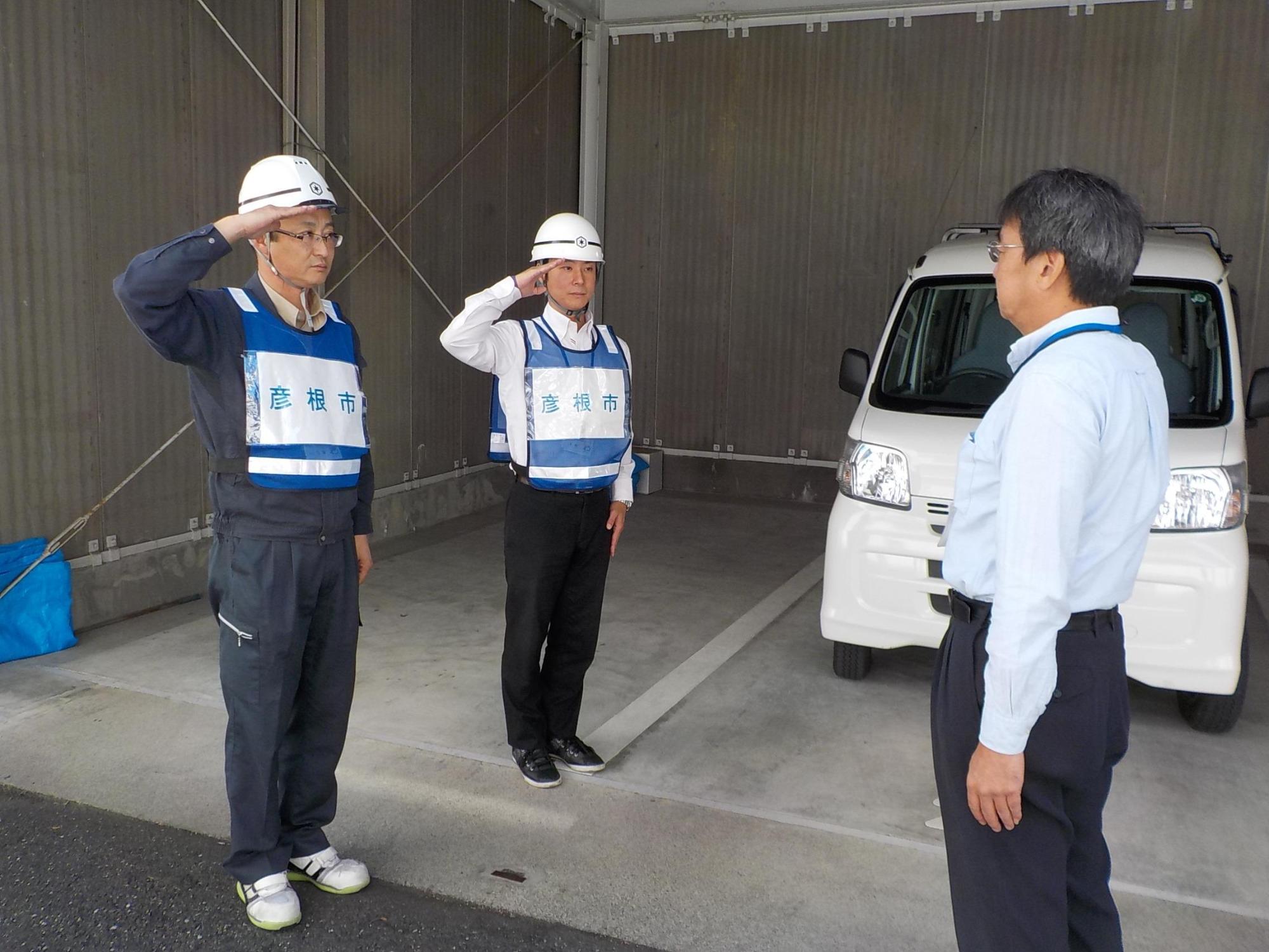 鳥取県に派遣される職員2名が出発前に敬礼をしている写真