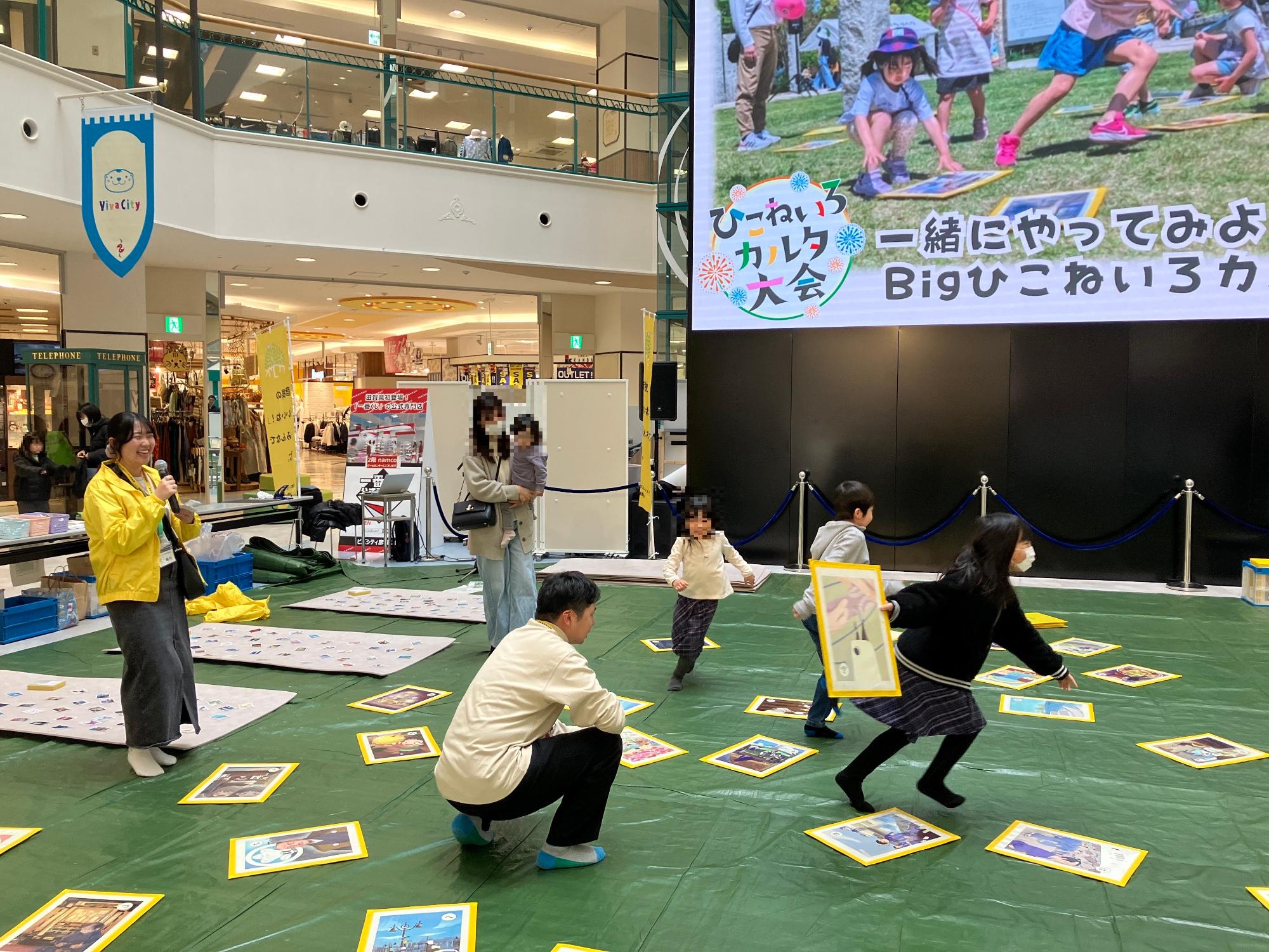 大きなカルタを使って子どもたちがカルタ取りをしている様子の写真