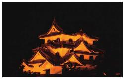オレンジ色にライトアップされた彦根城の写真