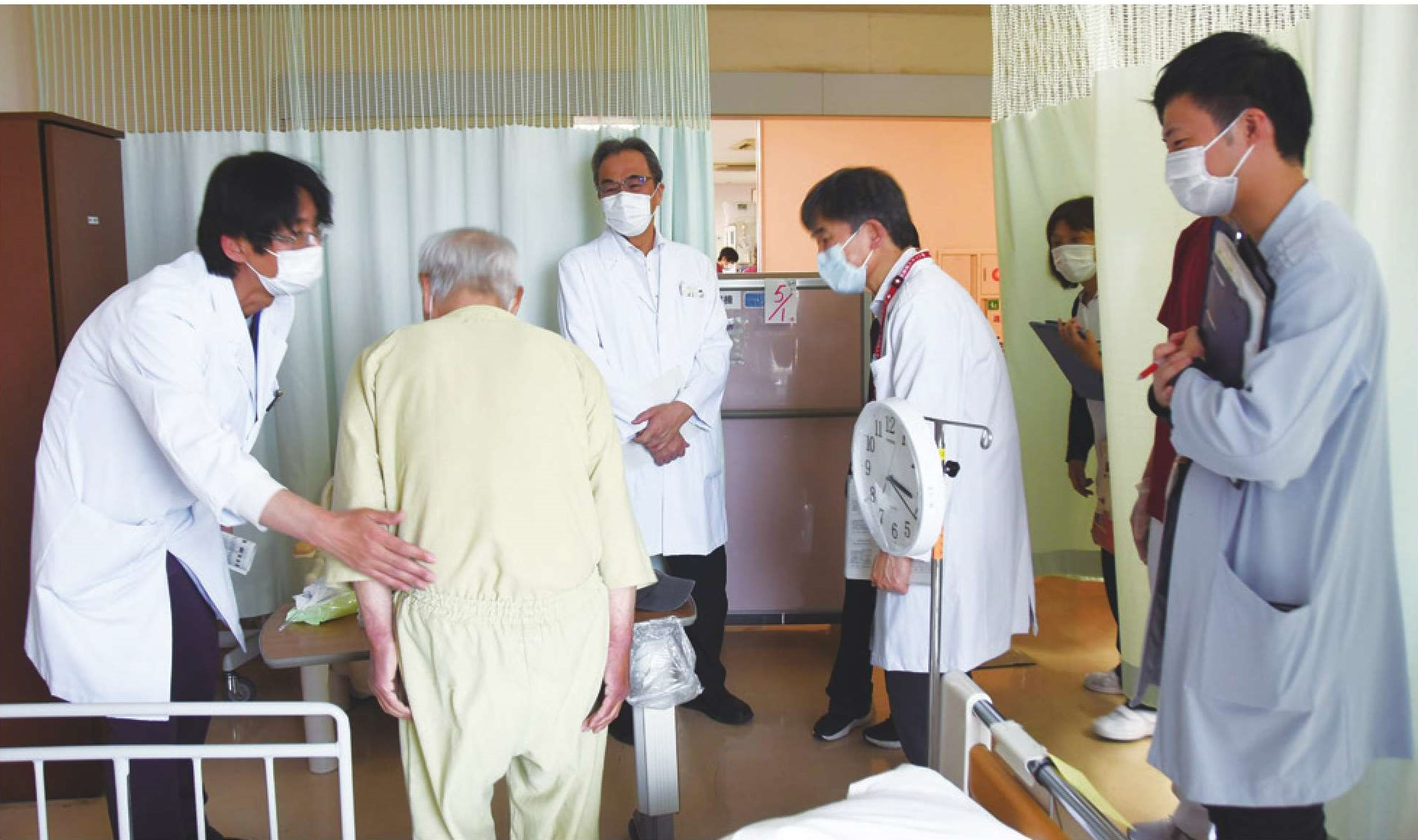 病室で、チームメンバーが患者さんを回診している様子の写真
