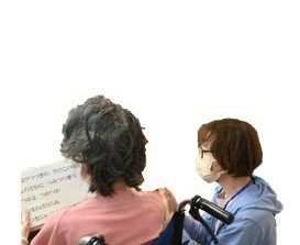 歌詞カードを持った車椅子に座る女性と、付き添う女性の写真