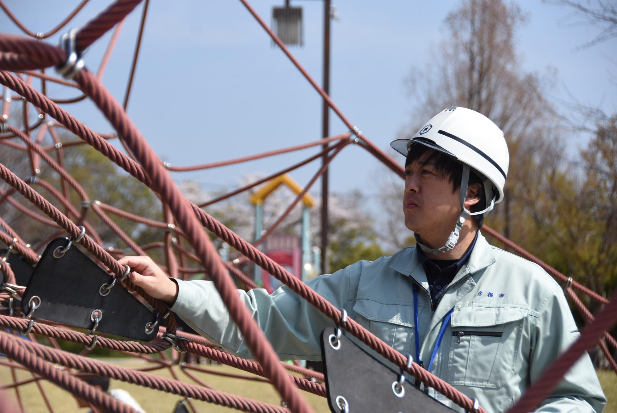 公園の遊具の点検をする、ヘルメット着用した石田さんの画像