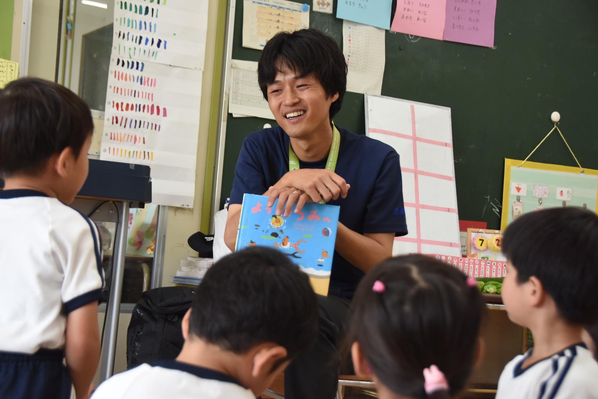 絵本を持つ戸田さんと、周りに集まった園児たちの写真