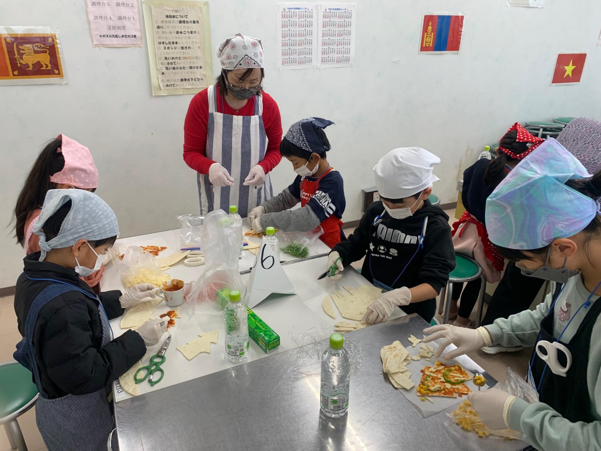 子どもたちがピザを作成している様子の写真