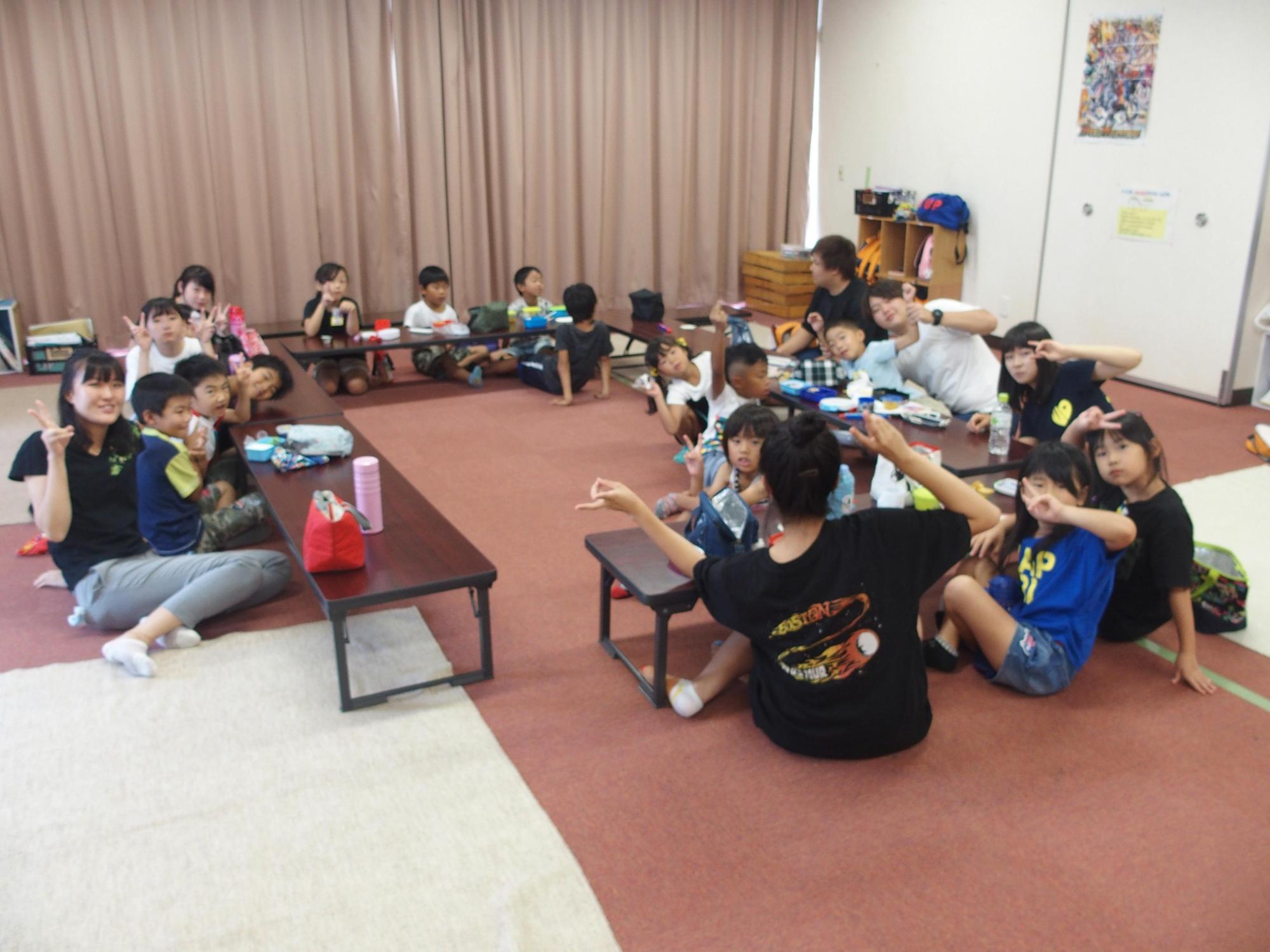 子どもたちと青年指導員が共にお弁当を食べている写真