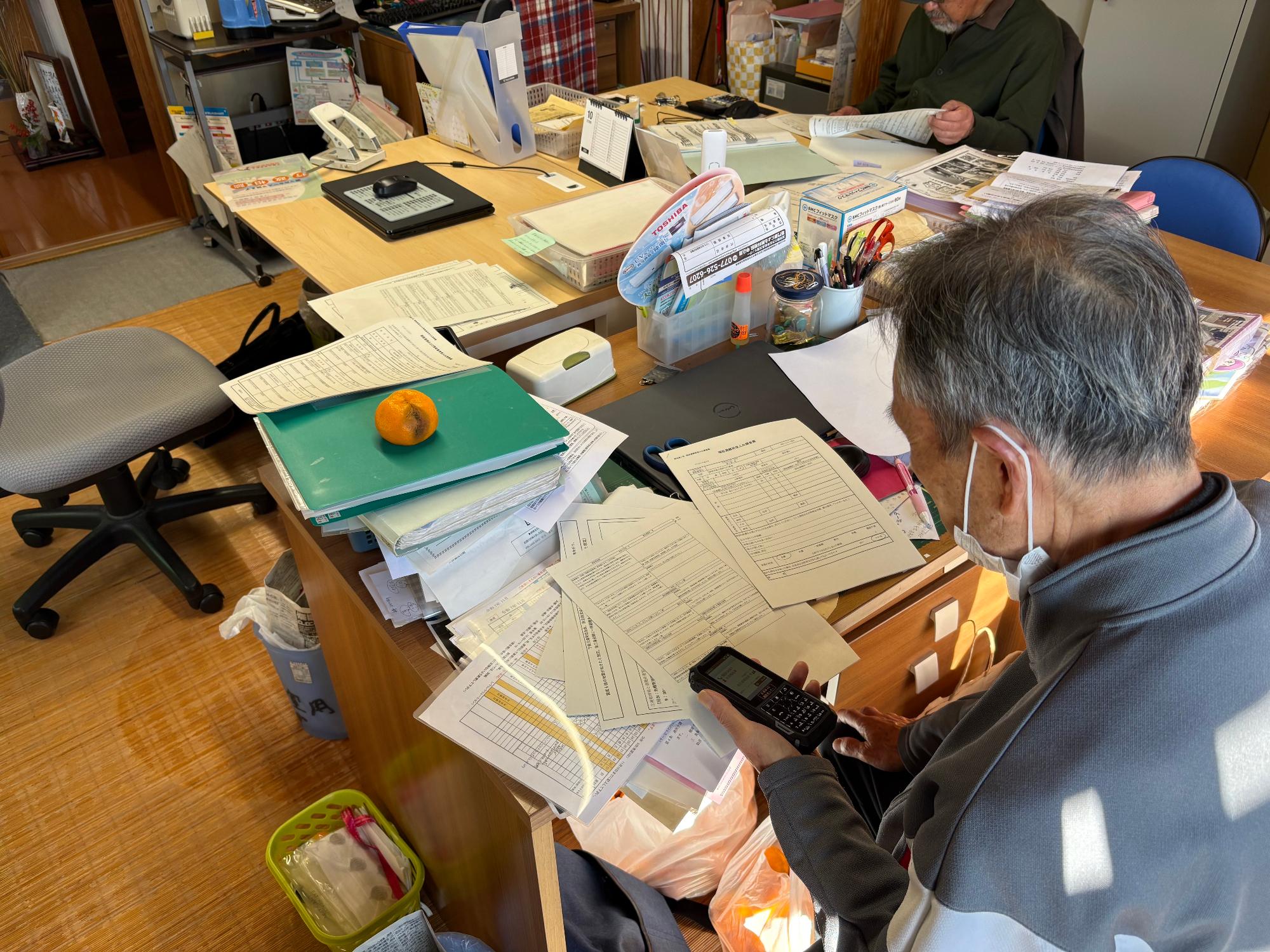 福祉避難所（デイホームぶどう）で机に座り無線機を持つ男性