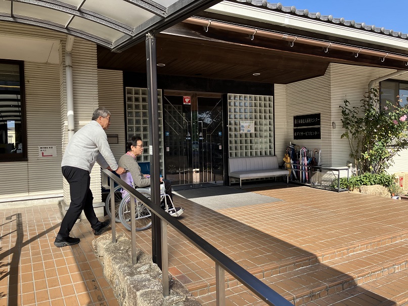 車椅子を男性がおして移動している様子