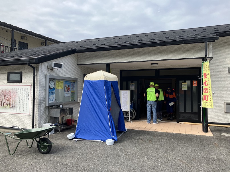 建物の前に、青い仮設テントが置かれている様子