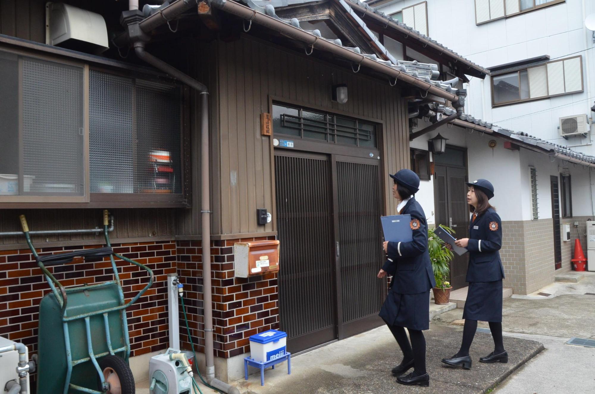 防火診断のため玄関前にいる制服をきた女性消防士二人の写真