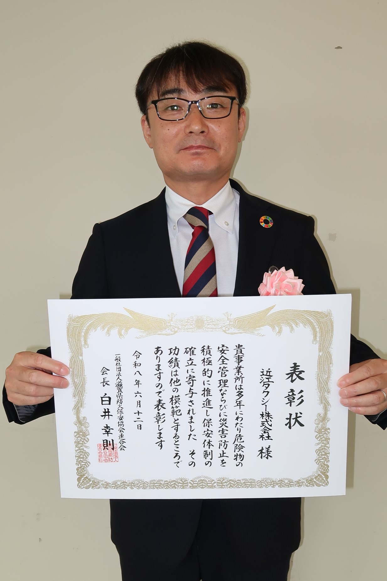 表彰状を両手で持つ男性