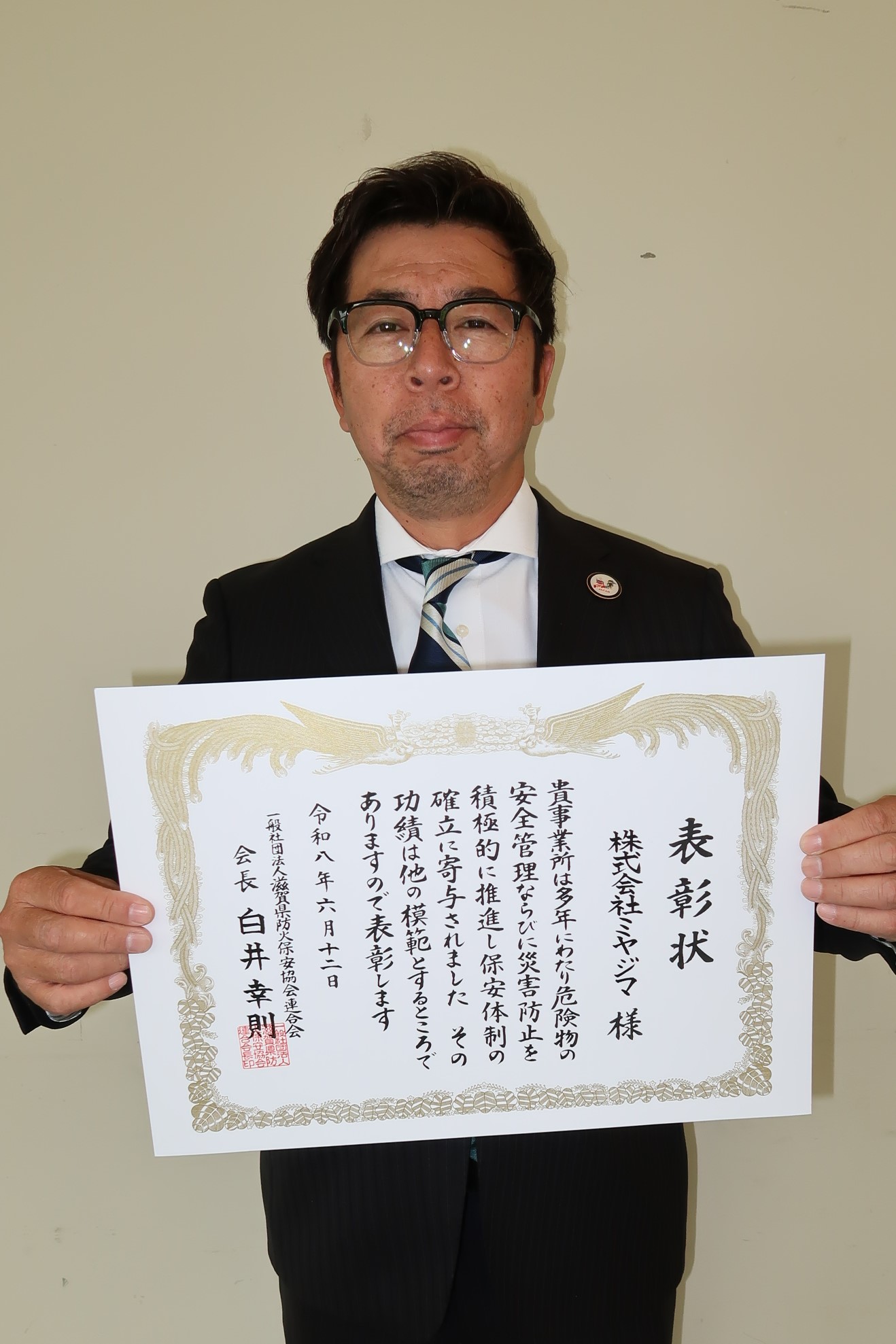 表彰状を両手で持つ男性
