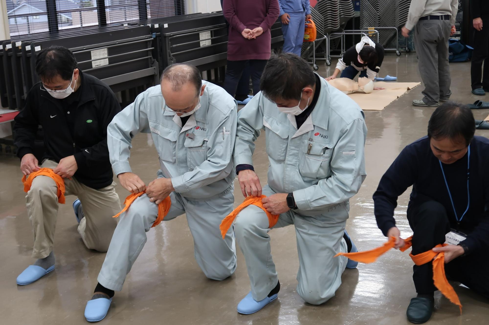 並んでひざに布を巻く練習をしている様子