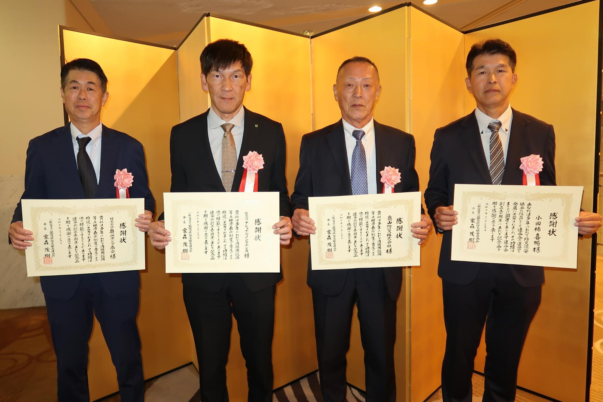 男性4名が金屏風の前で表彰状をもっている写真