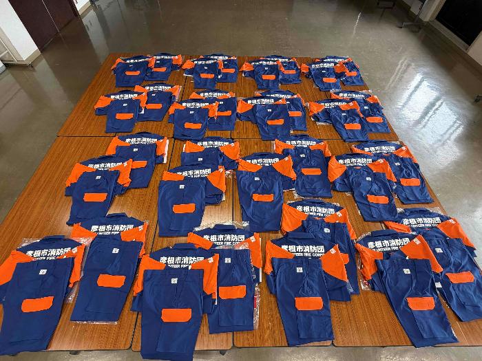 活動服上下32着が机の上に並べられた写真