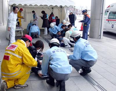 救急活動をしている救急隊員と担架にのせられて手当を受けている急病人の写真