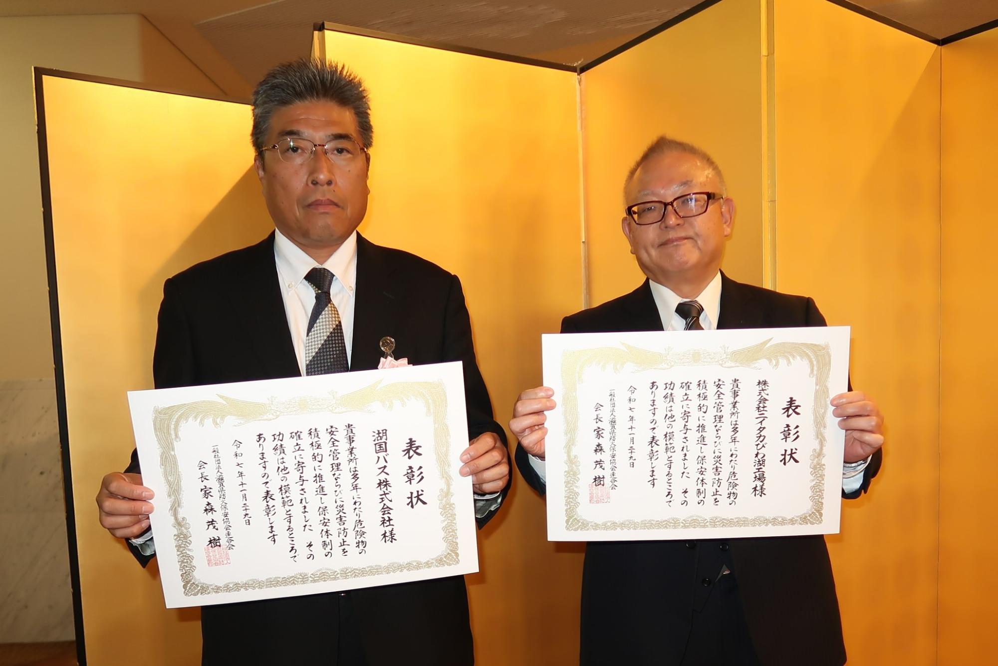 男性2名が金屏風の前で表彰状をもっている写真