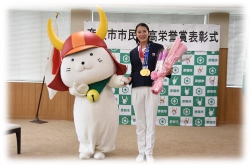 ひこにゃんとメダルをかけて花束を持った大橋選手の2ショット